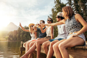 Young friends sitting on a dock toasting beers