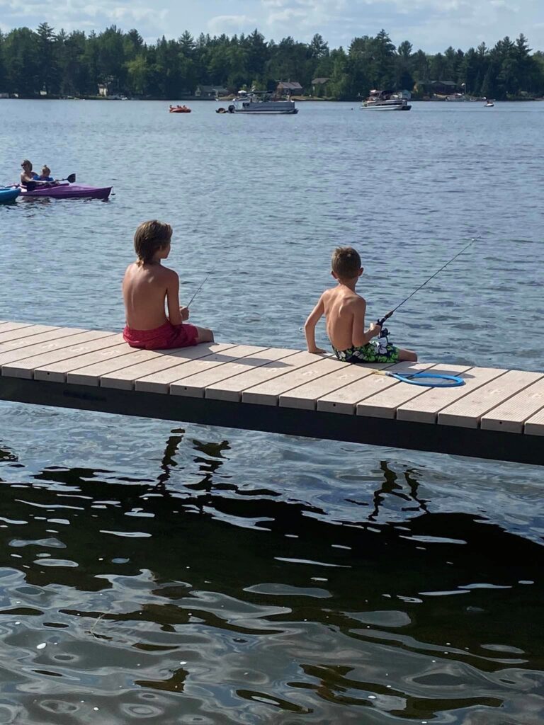 Two boys fishing off the side of a V-Dock